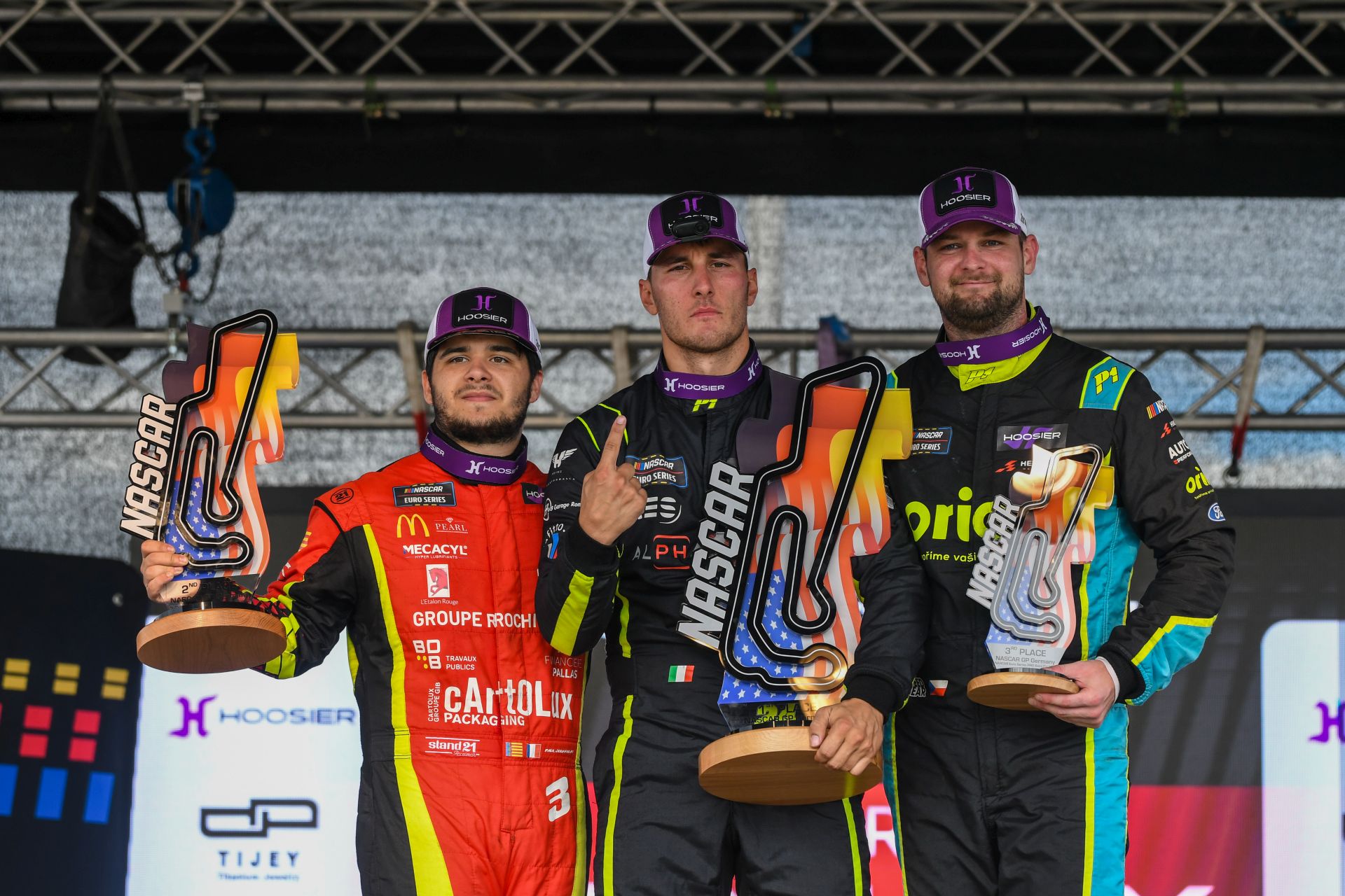 Vittorio Ghirelli (center) celebrates his win in the 2025 NASCAR GP Germany alongside Paul Jouffreau (left) and Martin Doubek (right)