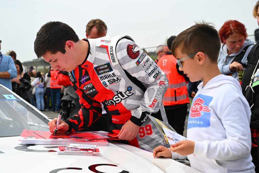 Garrett Lowe signs a hero card for a young fan during the 2025 Valencia NASCAR Fest at Circuit Ricardo Tormo
